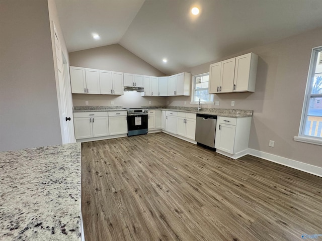 kitchen with white cabinets, stainless steel appliances, light stone countertops, and hardwood / wood-style flooring