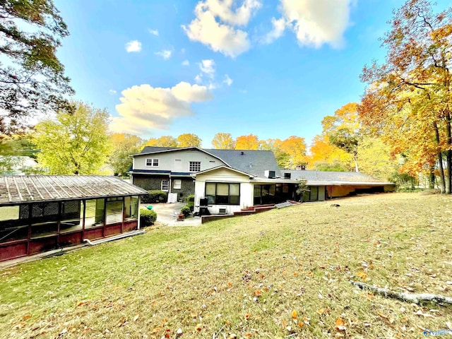 back of house featuring a sunroom and a lawn