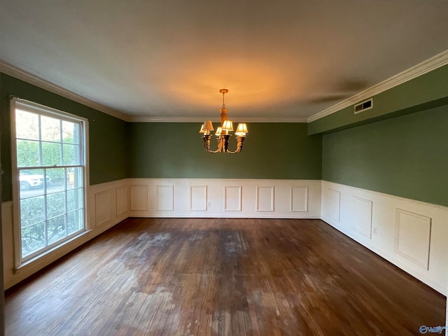 empty room featuring a chandelier, dark hardwood / wood-style floors, and ornamental molding