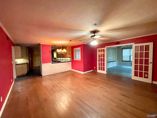 unfurnished living room featuring hardwood / wood-style floors, ceiling fan with notable chandelier, and ornamental molding