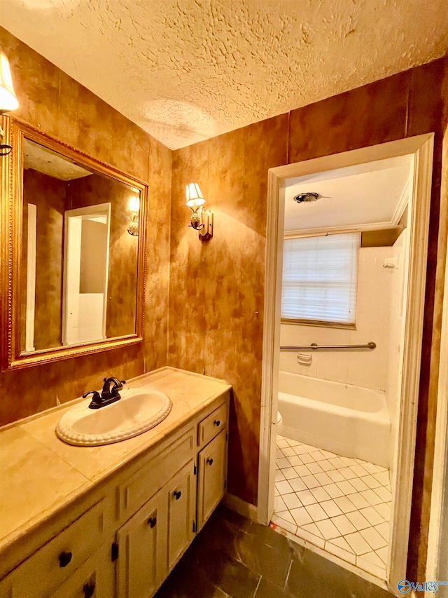 bathroom featuring tile patterned floors, vanity, a textured ceiling, and a washtub