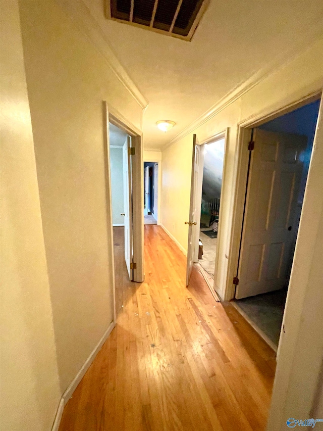 hall with light wood-type flooring and crown molding