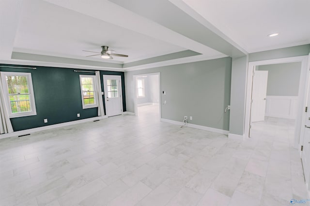 empty room with plenty of natural light, a tray ceiling, and ceiling fan