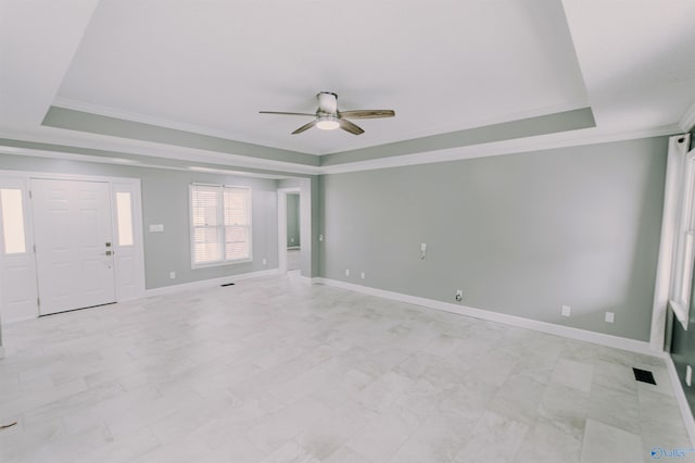 interior space featuring a tray ceiling, crown molding, baseboards, and a ceiling fan