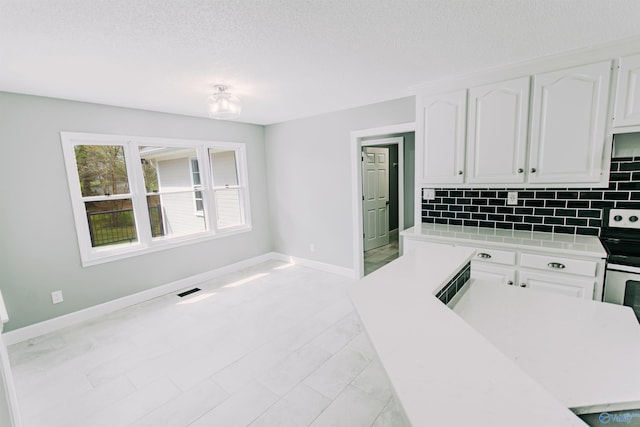 kitchen featuring baseboards, light countertops, backsplash, and white cabinetry