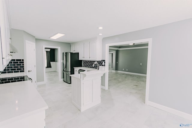 kitchen featuring white cabinets, baseboards, light countertops, a peninsula, and decorative backsplash