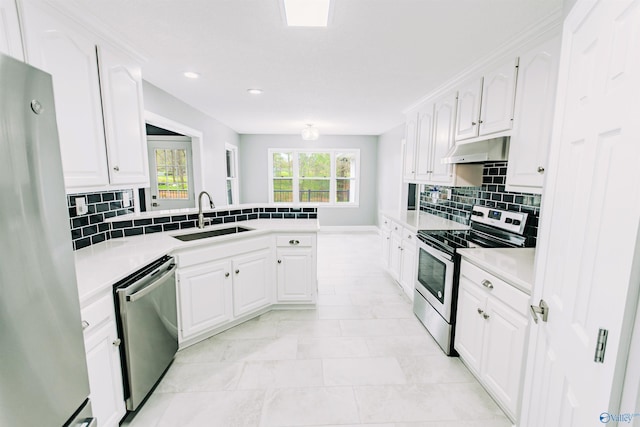 kitchen with a peninsula, white cabinets, appliances with stainless steel finishes, under cabinet range hood, and a sink