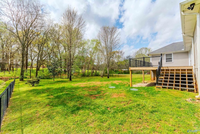 view of yard with fence, a wooden deck, and stairway