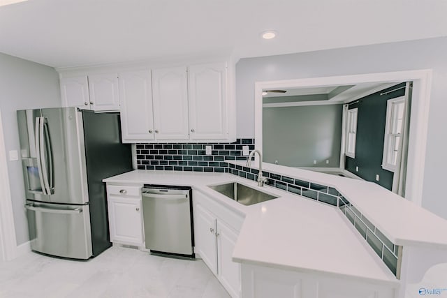 kitchen featuring a peninsula, light countertops, white cabinets, appliances with stainless steel finishes, and a sink