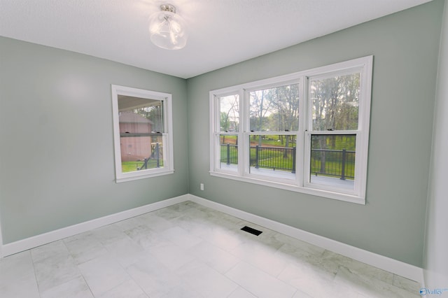 empty room featuring marble finish floor, visible vents, and baseboards