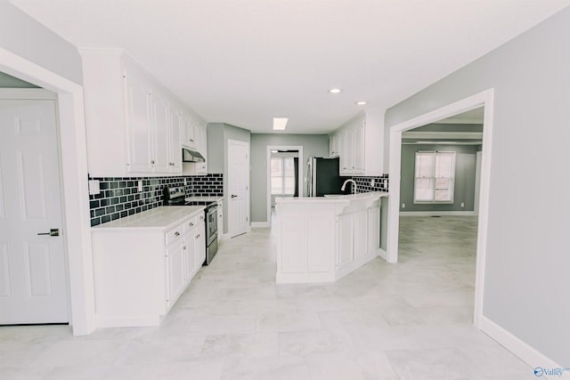 kitchen featuring stainless steel electric range oven, white cabinets, light countertops, freestanding refrigerator, and backsplash