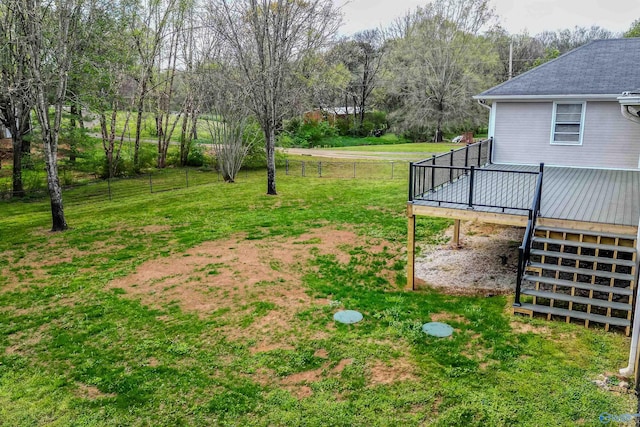 view of yard with fence, a deck, and stairs