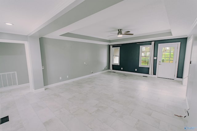 spare room featuring a tray ceiling, ceiling fan, baseboards, and visible vents