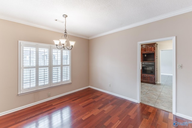 spare room with crown molding, dark wood-type flooring, a textured ceiling, and a chandelier