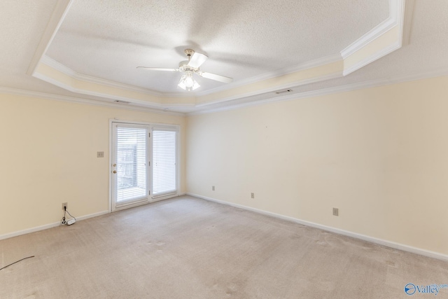 unfurnished room with ornamental molding, light carpet, a textured ceiling, and a tray ceiling