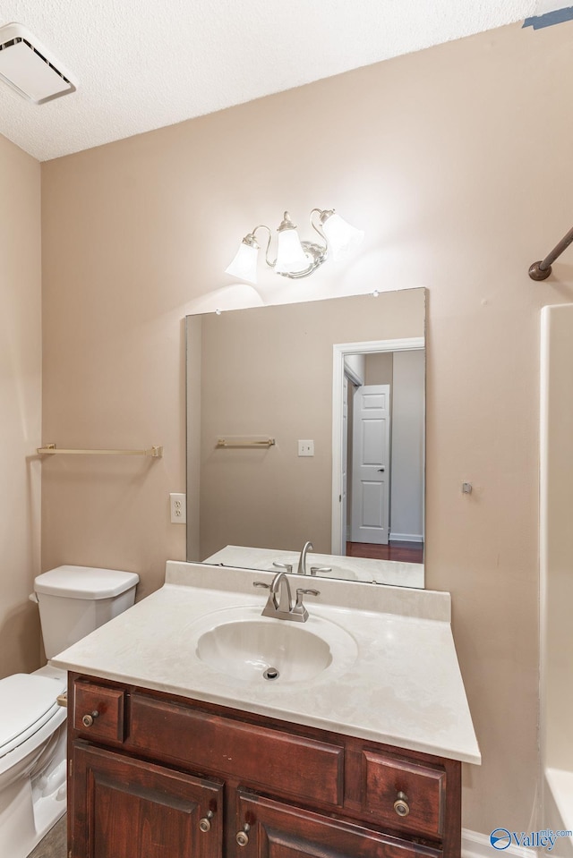 bathroom featuring vanity, a textured ceiling, and toilet