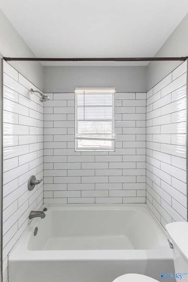 bathroom with toilet and tiled shower / bath combo