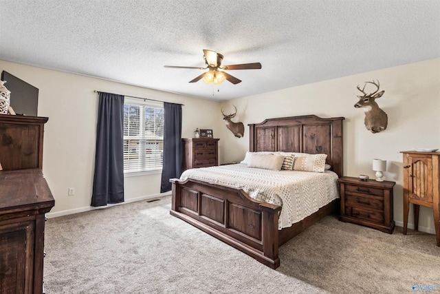 bedroom with ceiling fan, light carpet, and a textured ceiling