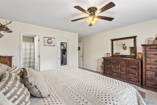 carpeted bedroom with ceiling fan, ensuite bath, and a textured ceiling