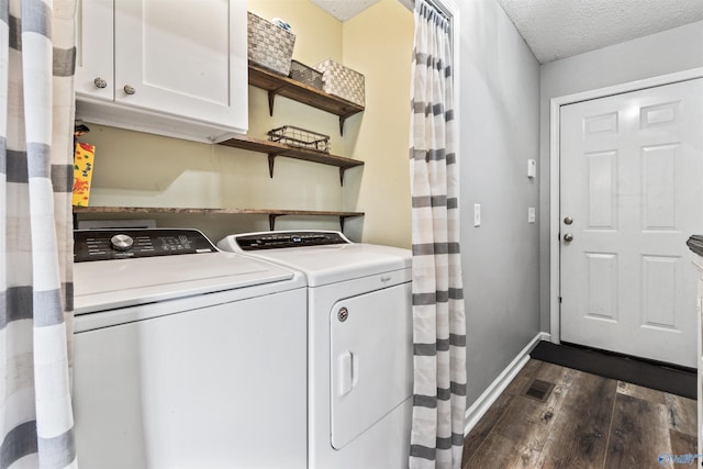 washroom with dark wood-type flooring, cabinets, washing machine and dryer, and a textured ceiling