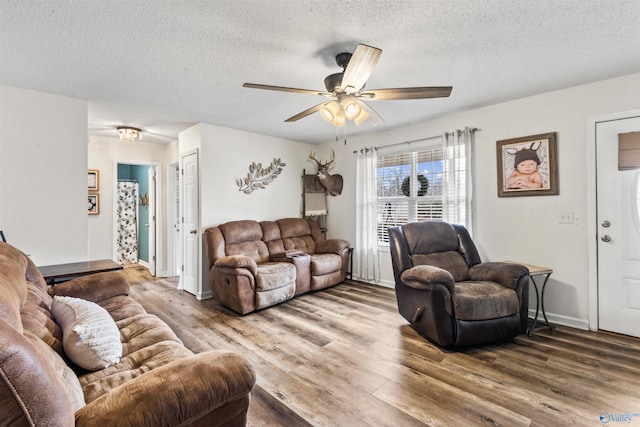 living room featuring ceiling fan, wood-type flooring, and a textured ceiling