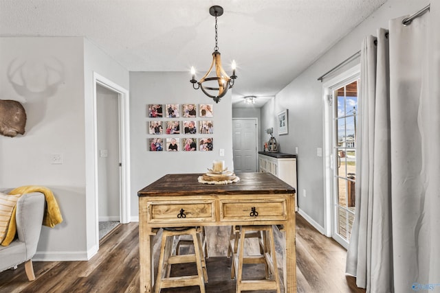 dining space featuring dark wood-type flooring, an inviting chandelier, and a textured ceiling