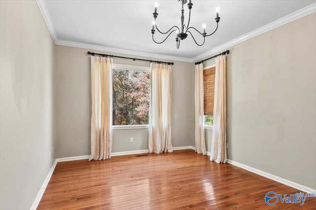 unfurnished room featuring hardwood / wood-style floors, an inviting chandelier, a wealth of natural light, and ornamental molding