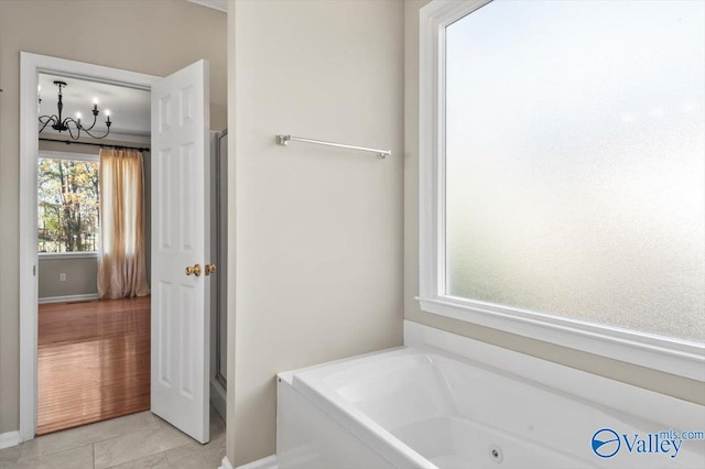 bathroom featuring tile patterned floors, a bathing tub, and an inviting chandelier