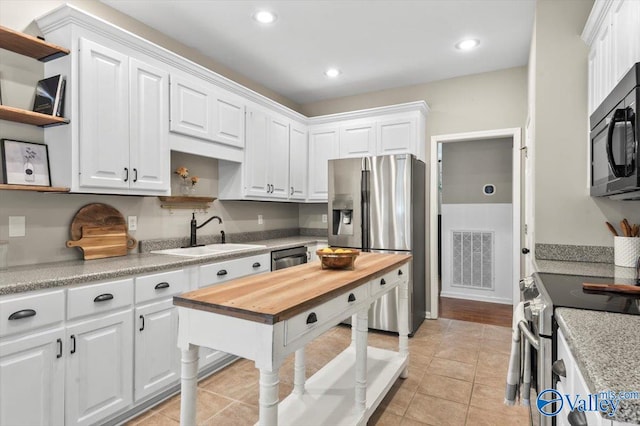 kitchen featuring sink, white cabinets, light tile patterned floors, and appliances with stainless steel finishes