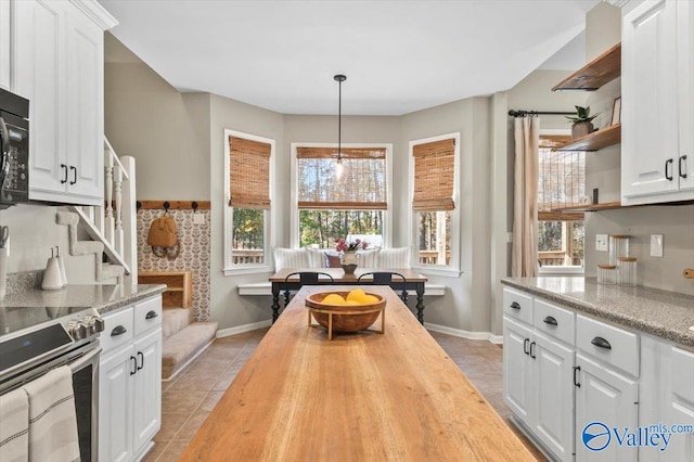 kitchen featuring light tile patterned floors, stainless steel range, butcher block countertops, decorative light fixtures, and white cabinetry