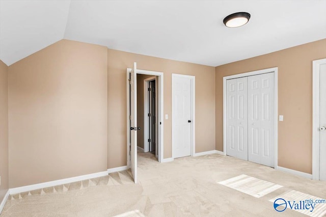 unfurnished bedroom featuring light colored carpet, a closet, and lofted ceiling