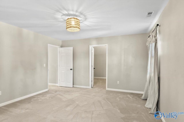 empty room with light carpet and a notable chandelier