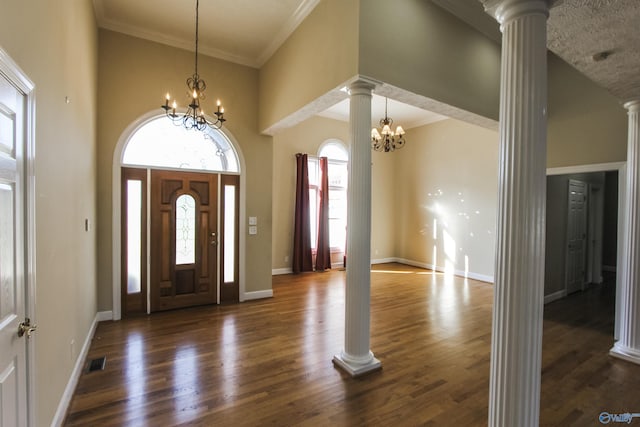 entrance foyer featuring decorative columns, dark hardwood / wood-style floors, and an inviting chandelier