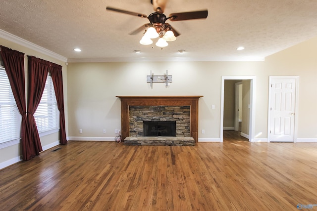 unfurnished living room with a stone fireplace, ceiling fan, ornamental molding, a textured ceiling, and wood-type flooring