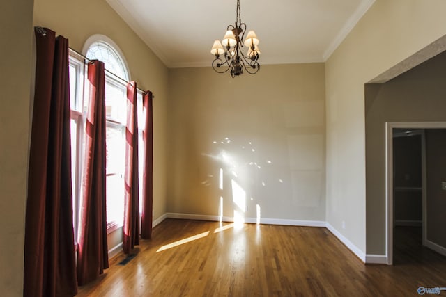 empty room with dark hardwood / wood-style flooring, crown molding, and a notable chandelier