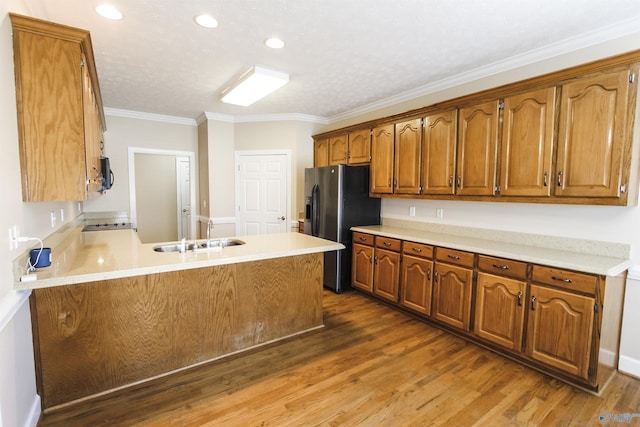 kitchen featuring sink, dark hardwood / wood-style floors, stainless steel refrigerator with ice dispenser, kitchen peninsula, and ornamental molding