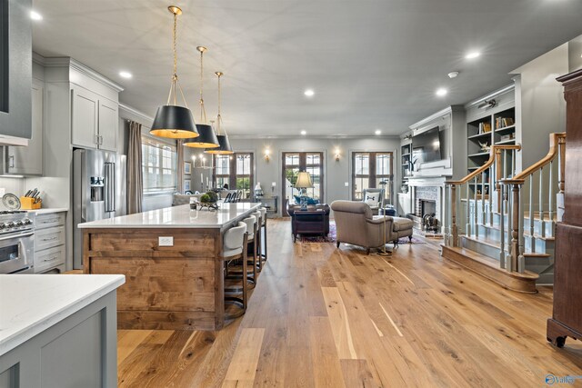 kitchen featuring light hardwood / wood-style flooring, stainless steel appliances, gray cabinetry, hanging light fixtures, and a center island