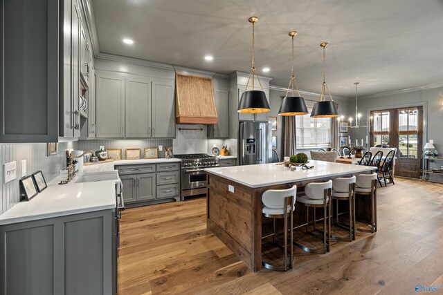 kitchen featuring a center island, gray cabinets, light hardwood / wood-style floors, custom exhaust hood, and appliances with stainless steel finishes