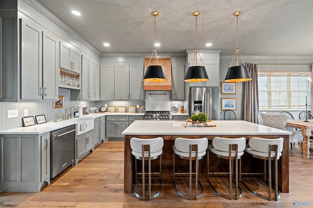 kitchen with a kitchen breakfast bar, a kitchen island, light wood-type flooring, and stainless steel appliances