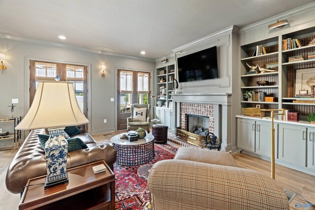 living room featuring light hardwood / wood-style flooring, built in shelves, a brick fireplace, and ornamental molding