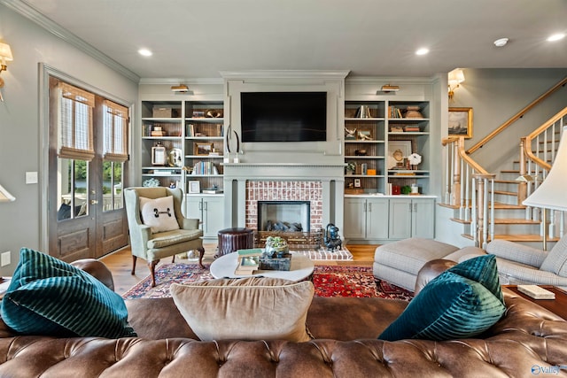 living room with built in features, crown molding, a fireplace, and hardwood / wood-style flooring