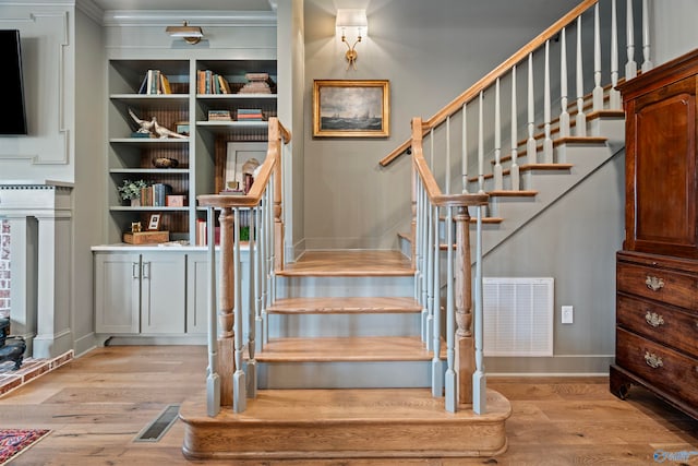 stairs with light hardwood / wood-style floors and ornamental molding