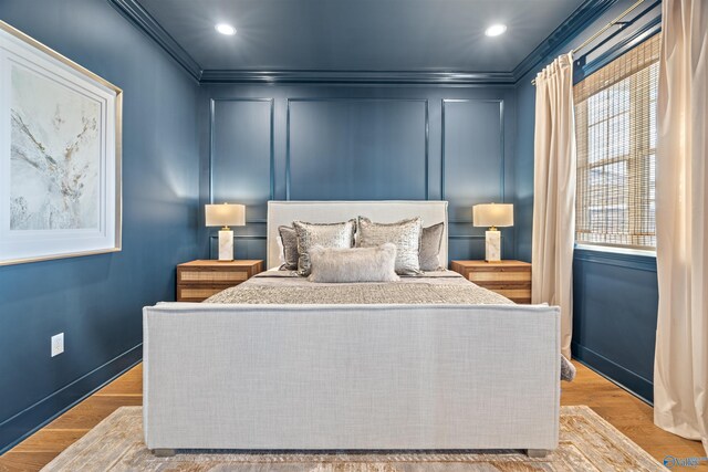 bedroom with light hardwood / wood-style floors, multiple windows, and ornamental molding