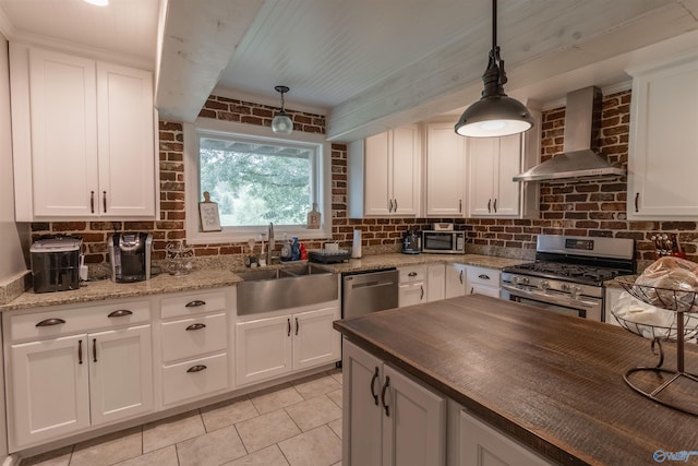 kitchen with wall chimney exhaust hood, tasteful backsplash, a sink, and stainless steel appliances