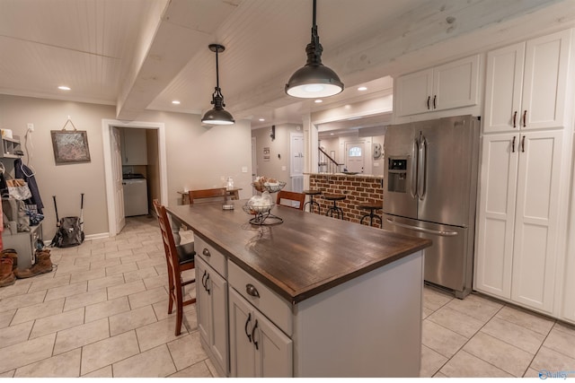 kitchen featuring light tile patterned flooring, wooden counters, stainless steel fridge with ice dispenser, washer / clothes dryer, and pendant lighting