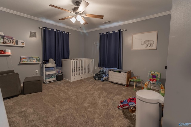 carpeted bedroom with a crib, a ceiling fan, visible vents, and crown molding