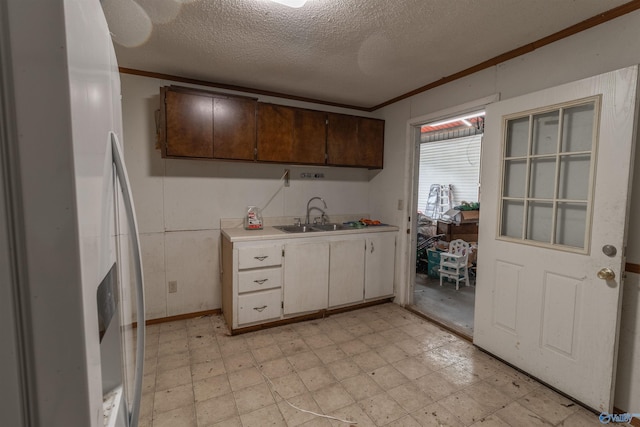 kitchen with light floors, white refrigerator with ice dispenser, light countertops, and a sink