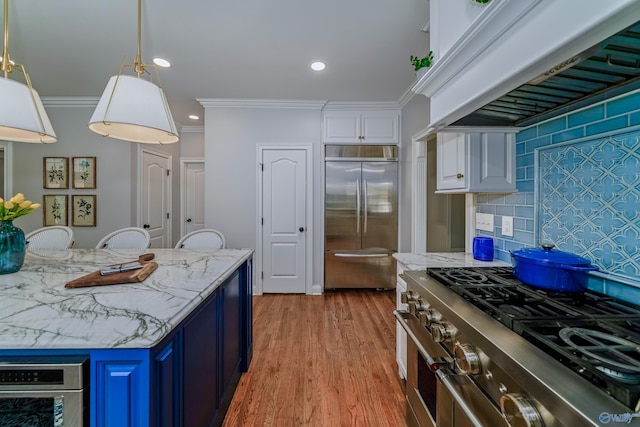 kitchen with blue cabinetry, high end appliances, premium range hood, white cabinets, and light hardwood / wood-style floors