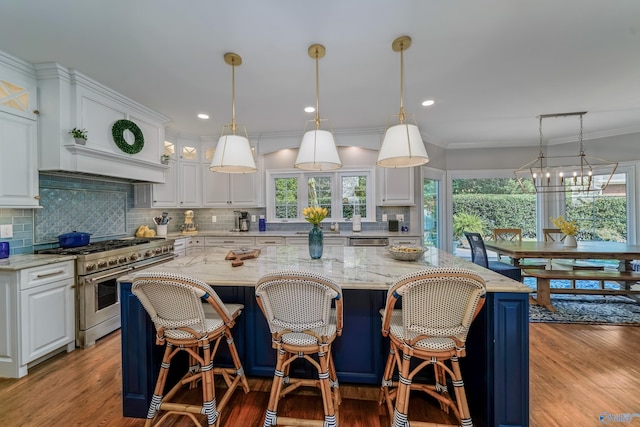 kitchen with decorative light fixtures, stainless steel appliances, wood-type flooring, a center island, and white cabinets