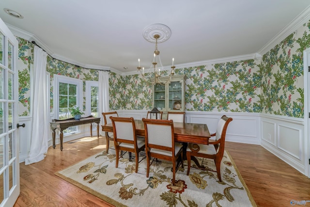 dining space with hardwood / wood-style flooring, a notable chandelier, and ornamental molding